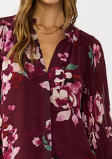 [Color: Wine/Dusty Rose] A detail image a brunette model wearing a burgundy floral blouse with long voluminous pleated sleeves, split v-neckline, and a hidden button front. Perfect for the office, holidays, or other special occasions. 