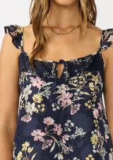 [Color: Navy/Yellow] A detail image a navy floral top with burnout details. Featuring an adjustable straps with ruffle detail, a scoop neckline with tie detail, and lace trim. A feminine and romantic top for the fall season. 
