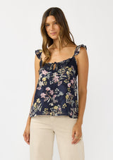 [Color: Navy/Yellow] A front facing image a navy floral top with burnout details. Featuring an adjustable straps with ruffle detail, a scoop neckline with tie detail, and lace trim. A feminine and romantic top for the fall season. 