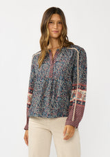 [Color: Navy/Rose] A front facing image of a brunette model wearing a navy floral border print blouse with a button front and long sleeves with lace trim accents.