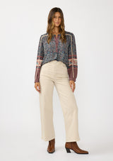 [Color: Navy/Rose] A front facing image of a brunette model wearing a navy floral border print blouse with a button front and long sleeves with lace trim accents.