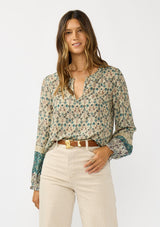 [Color: Taupe/Dusty Teal] A front facing image of a brunette model wearing a green teal floral blouse with a split v-neckline, lace accent on sleeves, and ruffled elastic cuffs. A fall boho blouse for casual styling. 