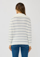 [Color: White/Blue] A back facing image of a brunette model wearing a white and blue striped knit pullover sweater with a half zip front. 