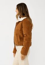[Color: Camel] A side facing image of a brunette model wearing a brown corduroy puffer jacket with a sherpa collar, zip-up front, and welt pockets. 