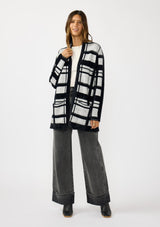 [Color: Black/Grey] A front facing image of a brunette model wearing a black and grey fuzzy plaid cardigan with an open front and patch pockets. A cozy cardigan for the fall season. 