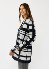 [Color: Black/Grey] A side facing image of a brunette model wearing a black and grey fuzzy plaid cardigan with an open front and patch pockets. A cozy cardigan for the fall season. 