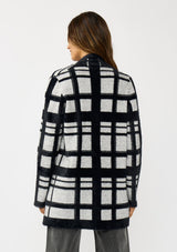 [Color: Black/Grey] A back facing image of a brunette model wearing a black and grey fuzzy plaid cardigan with an open front and patch pockets. A cozy cardigan for the fall season. 