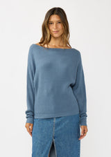 [Color: Cream] A front facing image of a brunette model wearing a blue waffle knit pullover sweater. With long sleeves, a relaxed fit, and a wide neckline that can be worn off the shoulder.