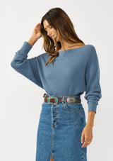[Color: Cream] A front facing image of a brunette model wearing a blue waffle knit pullover sweater. With long sleeves, a relaxed fit, and a wide neckline that can be worn off the shoulder.
