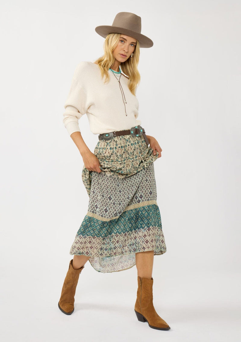 [Color: Taupe/Dusty Teal] A front facing image of a blonde model wearing a green teal floral bohemian skirt with an elastic drawstring waist and lace detail. A classic bohemian skirt for the fall season. 
