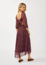 [Color: Wine/Rose] A back facing image of a blonde model wearing a floral diamond print chiffon maxi dress with metallic threads, a tie back, 3/4 sleeves, and a scoop neckline. A flattering special occasion dress for weddings or holidays. 