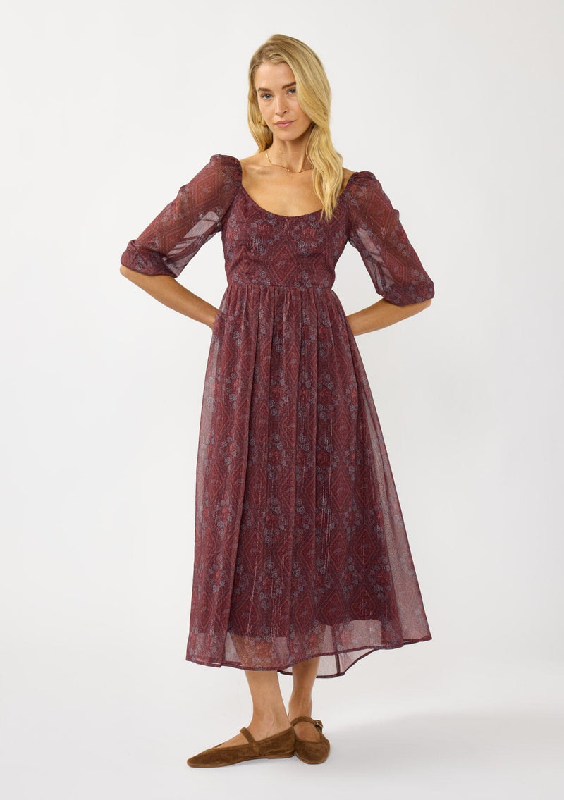 [Color: Wine/Rose] A front facing image of a blonde model wearing a floral diamond print chiffon maxi dress with metallic threads, a tie back, 3/4 sleeves, and a scoop neckline. A flattering special occasion dress for weddings or holidays. 