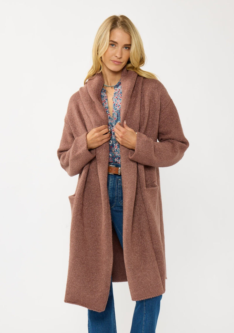 [Color: Vintage Mauve] A front facing image of a blonde model wearing a best selling oversized cardigan in a mauve color. A cozy and thick sweater coat with a hood, an open front, side pockets, a cocoon style silhouette, and a mid length hem. 