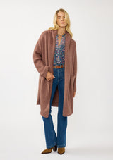 [Color: Vintage Mauve] A front facing image of a blonde model wearing a best selling oversized cardigan in a mauve color. A cozy and thick sweater coat with a hood, an open front, side pockets, a cocoon style silhouette, and a mid length hem. 