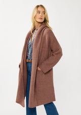 [Color: Vintage Mauve] A front facing image of a blonde model wearing a best selling oversized cardigan in a mauve color. A cozy and thick sweater coat with a hood, an open front, side pockets, a cocoon style silhouette, and a mid length hem. 
