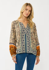 [Color: Natural/Rust] A front facing image of a blonde model wearing a yellow and orange floral blouse with a split v-neckline and long voluminous sleeves. A stunning bohemian fall blouse.