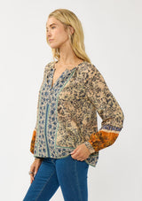 [Color: Natural/Rust] A side facing image of a blonde model wearing a yellow and orange floral blouse with a split v-neckline and long voluminous sleeves. A stunning bohemian fall blouse.