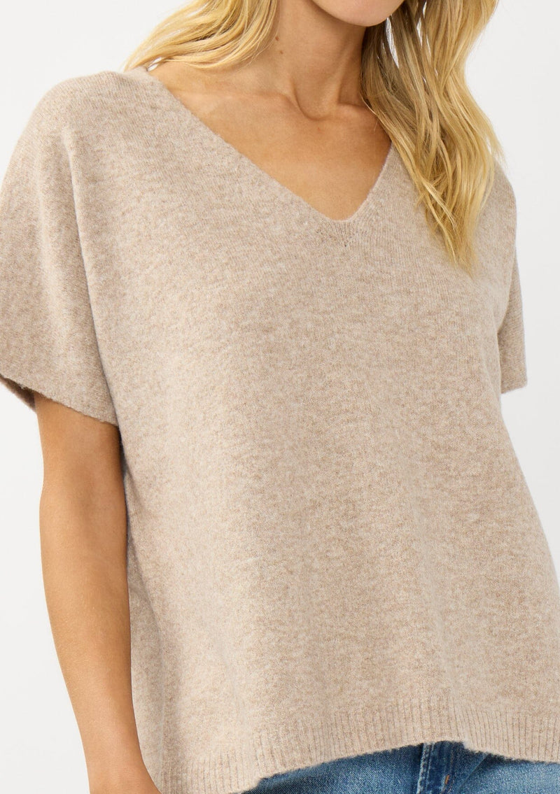 [Color: Heather Light Taupe] A detail image of a blonde model wearing a light brown sweater dop with short dolman sleeves and a v-neckline. Effortless and cozy for cold weather outings. 
