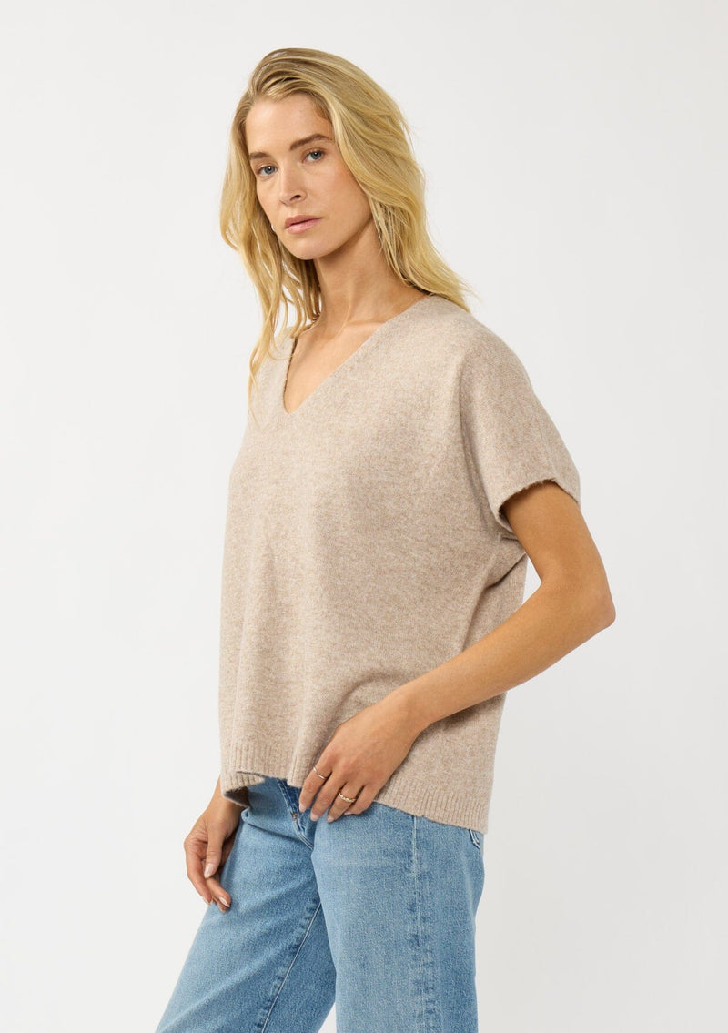 [Color: Heather Light Taupe] A side facing image of a blonde model wearing a light brown sweater dop with short dolman sleeves and a v-neckline. Effortless and cozy for cold weather outings. 
