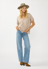 [Color: Heather Light Taupe] A front facing image of a blonde model wearing a light brown sweater dop with short dolman sleeves and a v-neckline. Effortless and cozy for cold weather outings. 