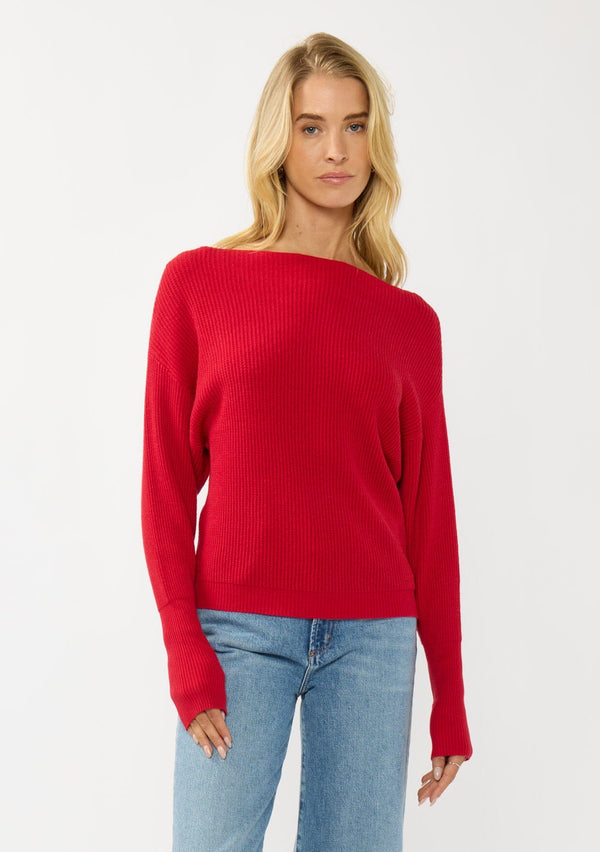 [Color: Red] A front facing image of a blonde model wearing a red waffle knit pullover sweater. With long sleeves, a relaxed fit, and a wide neckline that can be worn off the shoulder.