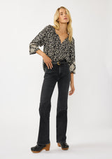 [Color: Black/Natural] A front facing image of a blonde model wearing an abstract print blouse with embroidered details, long sleeves, a button front, and a split v-neckline. 