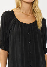 [Color: Black] A detail image of a blonde model wearing a plaid chiffon top with puff sleeves, a scoop neckline, and button front. 