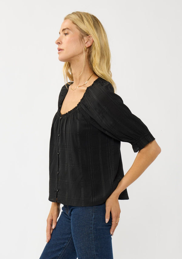 [Color: Black] A side facing image of a blonde model wearing a plaid chiffon top with puff sleeves, a scoop neckline, and button front. 