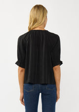 [Color: Black] A back facing image of a blonde model wearing a plaid chiffon top with puff sleeves, a scoop neckline, and button front. 