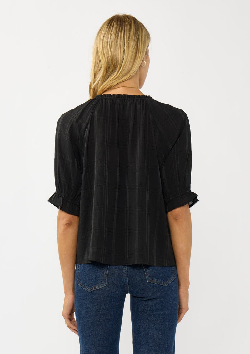 [Color: Black] A back facing image of a blonde model wearing a plaid chiffon top with puff sleeves, a scoop neckline, and button front. 