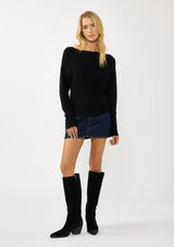 [Color: Black] A front facing image of a blonde model wearing a black waffle knit pullover sweater. With long sleeves, a relaxed fit, and a wide neckline that can be worn off the shoulder.