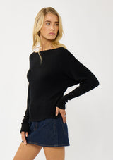 [Color: Black] A side facing image of a blonde model wearing a black waffle knit pullover sweater. With long sleeves, a relaxed fit, and a wide neckline that can be worn off the shoulder.