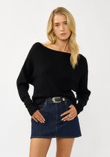 [Color: Black] A front facing image of a blonde model wearing a black waffle knit pullover sweater. With long sleeves, a relaxed fit, and a wide neckline that can be worn off the shoulder.