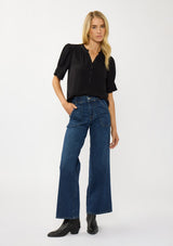 [Color: Black] A front facing image of a blonde model wearing a casual black puff sleeve top with a ruffled neckline, button front, and a gathered sleeve detail. Effortless and versatile for easy layering or wearing on its own. 