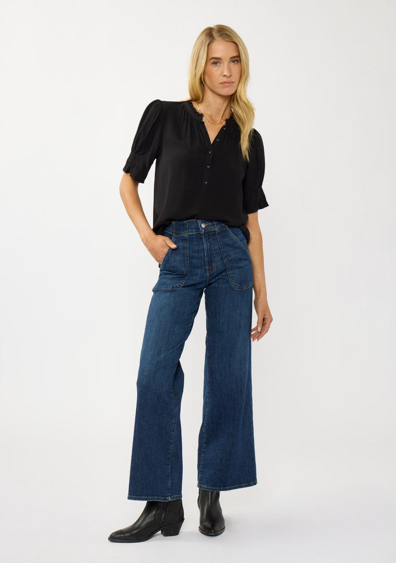 [Color: Black] A front facing image of a blonde model wearing a casual black puff sleeve top with a ruffled neckline, button front, and a gathered sleeve detail. Effortless and versatile for easy layering or wearing on its own. 