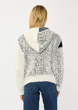 [Color: Cream/Black] A back facing image of a blonde model wearing a color block popcorn sweater jacket. A cozy textured sweater with a zipper front, hoodie, and long sleeves. 