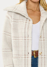 [Color: Cream/Taupe] A detail image of a blonde model wearing a plaid cozy sweater jacket with a wide collared neckline, button front, and front pockets. Cozy and fuzzy for the fall and winter season. 