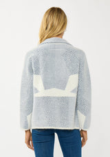 [Color: White/Dusty Blue] A back facing image of a blonde model wearing a blue striped sweater jacket with white geometric accents. Featuring a notched lapel, double-breasted front, snap buttons, and side pockets. A cozy and chic fall sweater for the office and casual outings. 