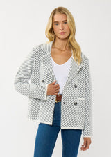 [Color: Black/White] A front facing image of a blonde model wearing a chevron stripe sweater jacket with a soft, fuzzy texture. Featuring a notched collar, double-breasted front, and patch pockets. Cozy and chic for cold weather styling. 