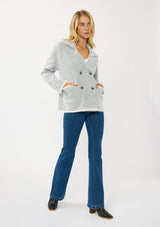 [Color: Black/White] A front facing image of a blonde model wearing a chevron stripe sweater jacket with a soft, fuzzy texture. Featuring a notched collar, double-breasted front, and patch pockets. Cozy and chic for cold weather styling. 