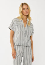 [Color: Grey/White] A front facing image of a blonde model wearing a cotton striped top with a surplice front, short dolman sleeves, and patch pockets. Paired with a matching bottom. 
