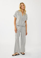 [Color: Grey/White] A front facing image of a blonde model wearing a cotton striped top with a surplice front, short dolman sleeves, and patch pockets. Paired with a matching bottom. 