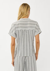 [Color: Grey/White] A back facing image of a blonde model wearing a cotton striped top with a surplice front, short dolman sleeves, and patch pockets. Paired with a matching bottom. 
