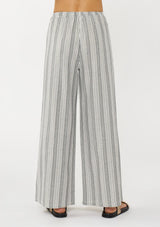 [Color: Grey/White] A back facing image of a blonde model wearing a grey striped bottom crafted in airy cotton with an elastic drawstring waist and wide legs. Effortless and breezy for vacation and resort styling. 