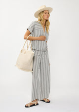 [Color: Grey/White] A front facing image of a blonde model wearing a grey striped top and bottom set for vacation and resort styling. 