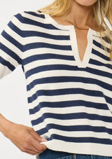 [Color: Cream/Navy] A detail image of a blonde model wearing a navy striped sweater top with short sleeves and a split v-neckline. A lightweight layer for resort season. 