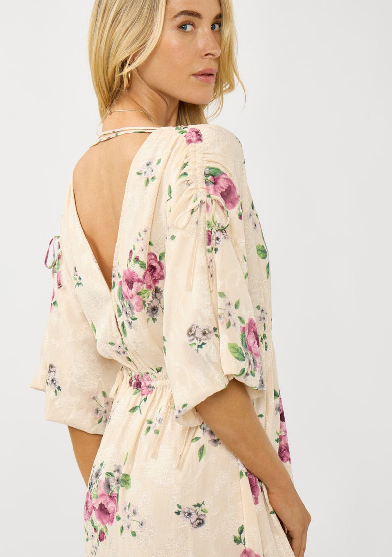 [Color: Natural/Dusty Rose] A detail image of a blonde model wearing floral jacquard midi dress with a rose floral print. Featuring ruched details, puff sleeves, v-neckline, and a chic open back. A feminine dress for special occasions and holidays. 