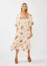 [Color: Natural/Dusty Rose] A front facing image of a blonde model wearing floral jacquard midi dress with a rose floral print. Featuring ruched details, puff sleeves, v-neckline, and a chic open back. A feminine dress for special occasions and holidays. 