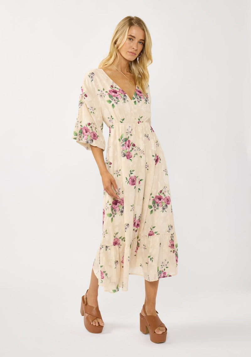 [Color: Natural/Dusty Rose] A front facing image of a blonde model wearing floral jacquard midi dress with a rose floral print. Featuring ruched details, puff sleeves, v-neckline, and a chic open back. A feminine dress for special occasions and holidays. 
