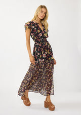 [Color: Black/Rust] A side facing image of a blonde model wearing a black floral maxi dress with short flutter sleeves, a split v-neckline, a smocked waist, and side slit. Adorned with ruffle trims, this romantic fall maxi dress is perfect for weddings, holidays, and other special occasions. 